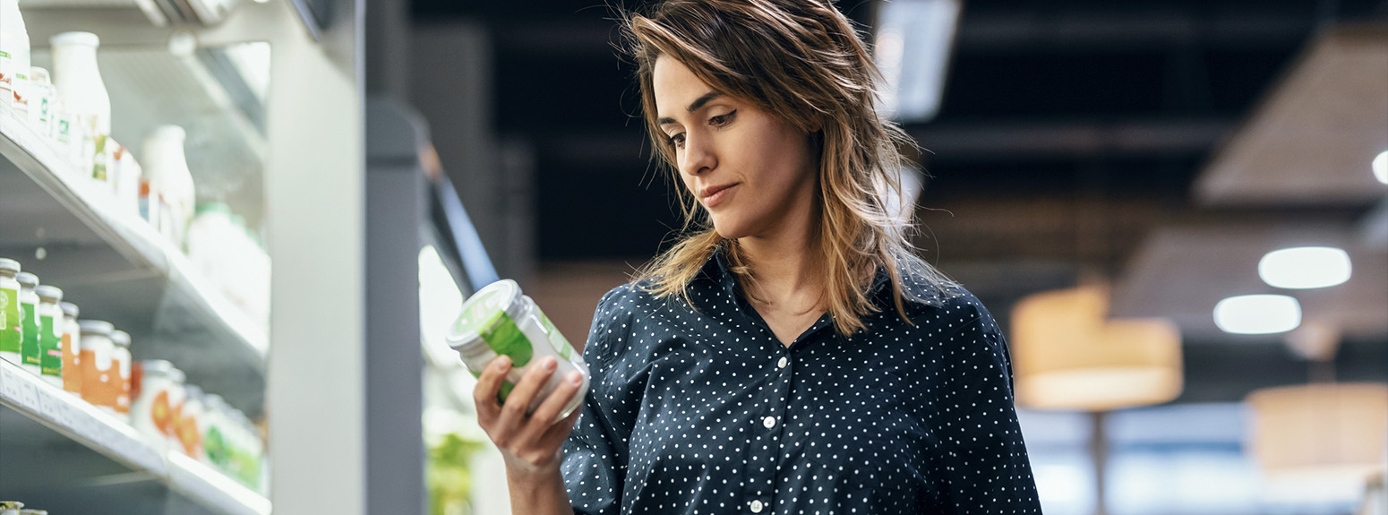 Donna al supermercato legge l'etichetta di un prodotto