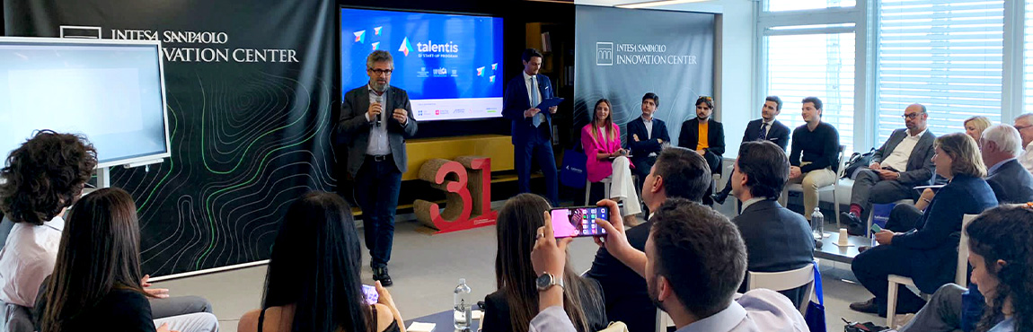 Image of the Talentis meeting at the Intesa Sanpaolo Innovation Center: man with microphone speaking in front of an audience