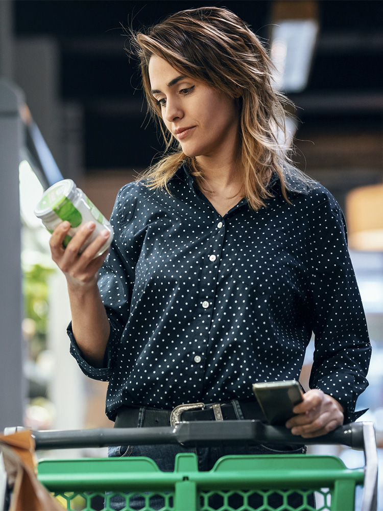 Donna al supermercato legge l'etichetta di un prodotto