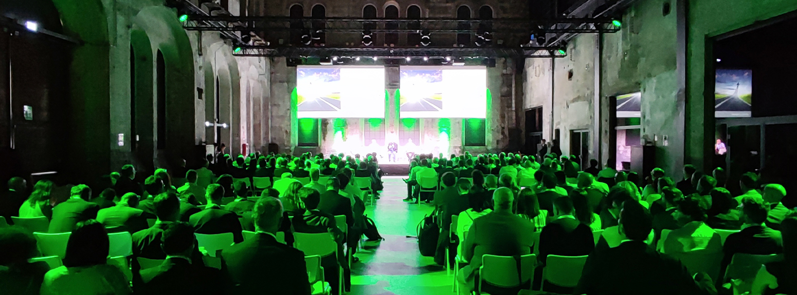 foto di persone in platea che seduti di spalle guardano il palco