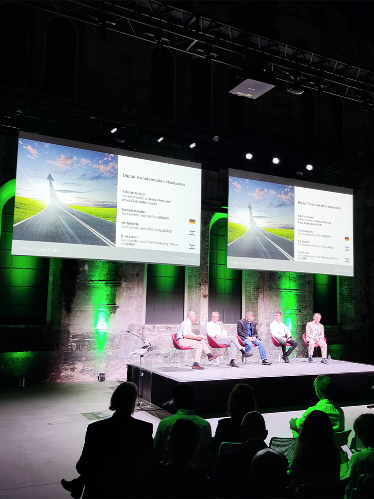 foto di persone in platea che seduti di spalle guardano il palco