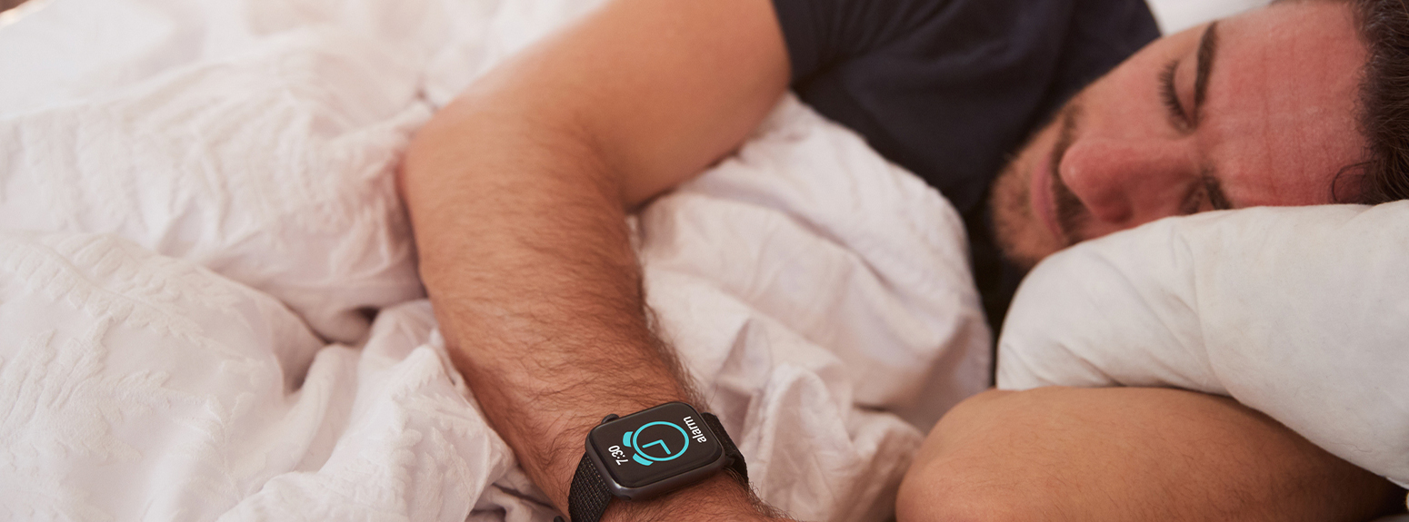 uomo a letto che guarda smartwatch